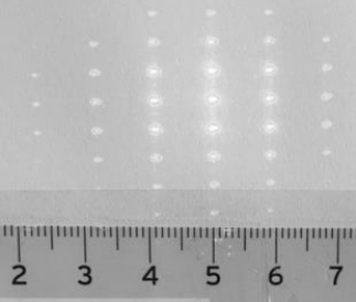 Lineal mit Zentimeter-Skala und darüber mehrere vertikale Reihen heller Lichtpunkte.